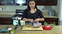 a woman standing in a kitchen preparing food on top of a wooden cutting board with utensils