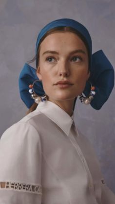 a woman in a white shirt and blue head scarf with large earrings on her ear