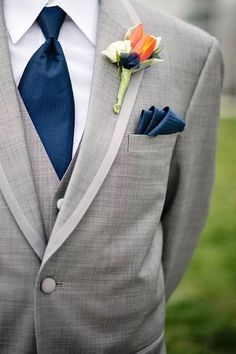 a man in a gray suit with a boutonniere on his lapel