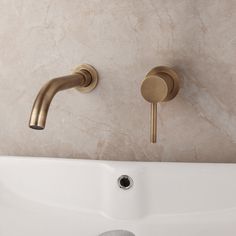 two brass faucets on the side of a white bathtub in a bathroom