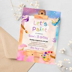 a birthday party card with an artistic painting theme on it and envelopes next to it