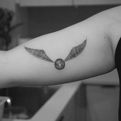 a black and white photo of an arm with a wing tattoo on the left forearm