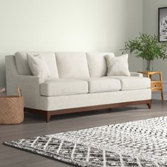 a white couch sitting on top of a hard wood floor next to a wooden table