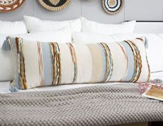 a bed with white pillows and decorative wall hangings on the headboard above it