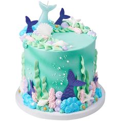 there is a blue cake decorated with mermaids and seaweed on the bottom layer