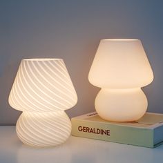 two white lamps sitting on top of a book