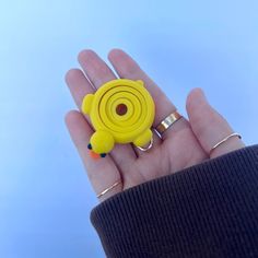 a hand holding a yellow ring with an animal on it's center and two rings in the middle