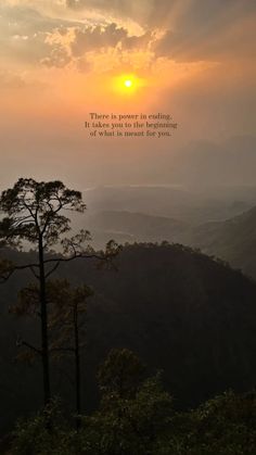 the sun is setting on top of a mountain with trees and mountains in the background