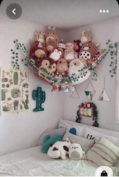 a bed with stuffed animals on the headboard and hanging plants above it in a bedroom