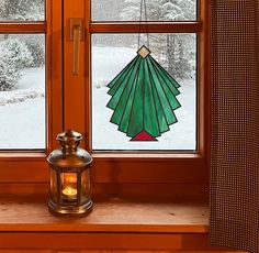 a lantern sitting on top of a window sill in front of a snow covered forest