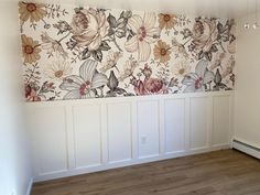 an empty room with white paneling and floral wallpaper on the walls, in front of a radiator