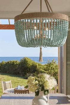 a chandelier hanging from the ceiling over a dining room table with white chairs