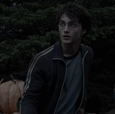 a young man wearing glasses sitting in front of pumpkins