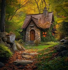 a small stone house in the woods surrounded by rocks and trees with leaves on them