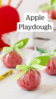 apples wrapped in cellophane and tied with green ribbon, sitting on a table