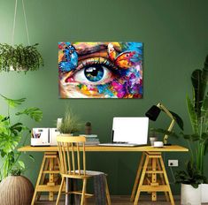 a painting on the wall above a desk with a laptop and chair in front of it