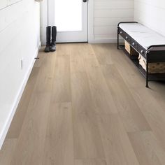 a wooden floor with a white door and black shoes on the bench next to it