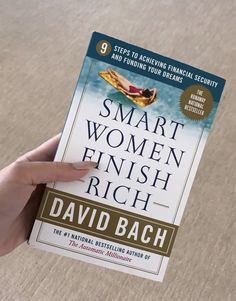 a person holding up a book about smart women finish rich in front of the camera