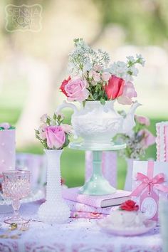 a table topped with a white vase filled with pink and white flowers next to other items