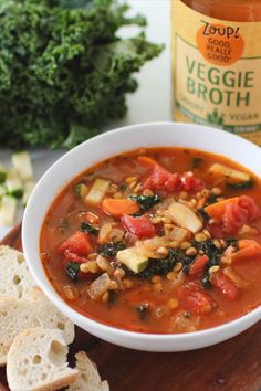 a bowl of vegetable soup next to some bread