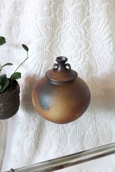 two potted plants sitting on top of a table next to a white cloth covered wall