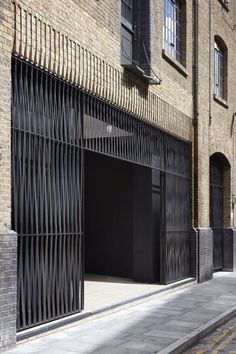 an open garage door on the side of a brick building with black iron bars and windows