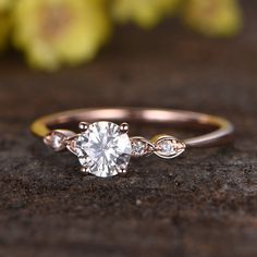 a close up view of a diamond ring on a wooden surface with flowers in the background