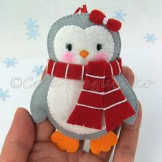 a small stuffed penguin with a red scarf on it's head is held in someones hand