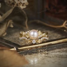 a pearl and diamond ring sitting on top of a table