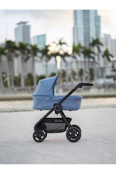 a blue stroller sitting on the ground in front of some buildings and palm trees