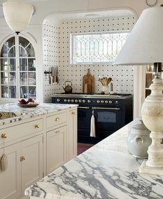 a large kitchen with white cabinets and marble counter tops