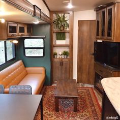 a living area with couch, coffee table and television in an rv kitchenette that is also used as a dining room