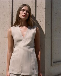 A classic wrap-style vest with a tie closure at the back, adjustable for a custom fit. Crafted from 100% European Flax® linen, it features a V-neckline and is transeasonal in wear and design. Style over the matching Lulea Pant for work to weekend wear. Fitted Unlined Linen Dress, Fitted Linen V-neck Dress For Daywear, Fitted Linen V-neck Dress For Work, Fitted V-neck Linen Dress For Work, Beige Linen V-neck Dress, Chic Beige V-neck Linen Dress, Fitted Linen V-neck Dress, Fitted Linen Dress For Work, Fitted Sleeveless Linen Dress For Work