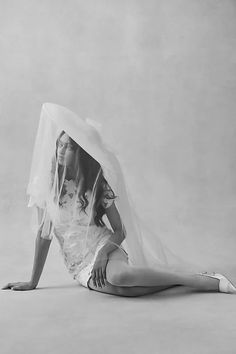 a black and white photo of a woman in a wedding dress laying on the floor