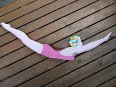 a paper cut out of a woman's body laying on a wooden floor with sprinkles