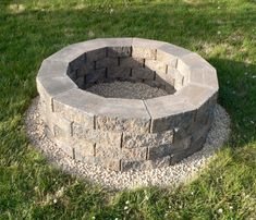 a stone fire pit sitting in the grass