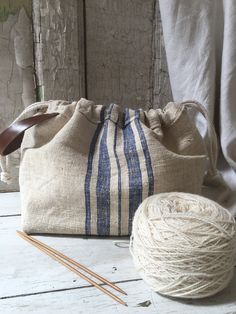 a ball of yarn next to a bag and knitting needles