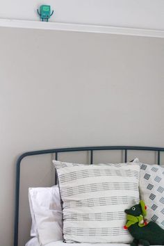 a bed with two pillows and a stuffed animal on top of it's headboard