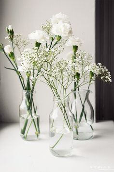 three glass vases with white flowers in them