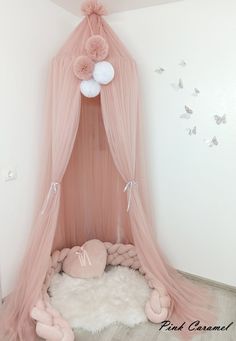 a pink canopy bed with pom poms on top