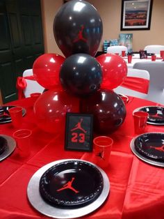 the table is set with black and red balloons, silverware, and air jordan plates