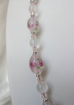 "This lampworked pink jewelry set is made with 14mm round frosted ovals with pink inlaid flowers. The 20\" necklace has a 3\" silver plated extender. Each oval is set off with silver plated heishe beads. Frosted 8mm rounds and pink bi-cone crystals are used between each lampwork bead. These beads are beautifully delicate and make a fine gift. The matching earrings dangle 1\" from the loops of the silver plated lever back wires. This set will be slipped into an organza bag and shipped in a bubble Pink Glass Round Jewelry, Pink Round Glass Jewelry, Pink Flower Glass Jewelry, Pink Flower-shaped Glass Jewelry, Flowers And Crystals, Blue Jewelry Set, Pink Jewelry Set, Lampwork Jewelry, Pink Jewelry