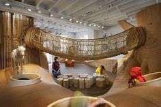 an indoor area with wooden structures and people working on the wood sculpture in the background