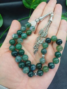 This listing is for 1 pc 33 beaded tasbih. Product Details: 💚 Bead size: 10 mm  💚 Bead count: 33 beads 💚 Bead cut: Round  💚 Gemstone: Moss Agate  💚 Spacers: Silver colored metals 💚 Gemstone Quality: AAA Grade (High Quality) 💚 Cord: Parachute thread ✔️ 33 beaded Islamic Misbaha ✔️ 10 mm big size Moss Agate gemstone Rosary  ✔️ Natural Green Color Tasbeeh  ✔️ Luxury Natural Aqiq Stone Tesbih  ✔️ High grade large Moss Aqeeq Stone beads ✔️ Silver colored metal aparats  ✔️ Strong Parachute thread  ✔️ This tasbih is perfect gift for friends, family members and loved ones. Note: As a natural feature the stones beads may have some variations. Metal aparats (imam, tassel,spacers) may be different from the photo due to stock position. If you have questions please do not hesitate to ask via dir Jade Beads Gems And Cabochons For Gifts, Jade Round Beads For Gifts, 8mm Agate Beads As Gifts, Round Agate Beads For Gifts, Spiritual Agate Beads, Spiritual Agate Round Beads, Spiritual Round Agate Beads, Polished Agate Beads For Gift, Gift Agate Polished Beads