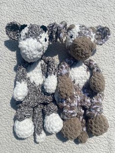 two crocheted stuffed animals laying next to each other on a white surface,