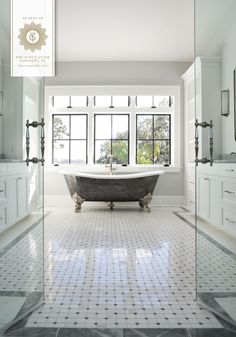 a large bathroom with a claw foot tub and marble tile flooring, along with two windows