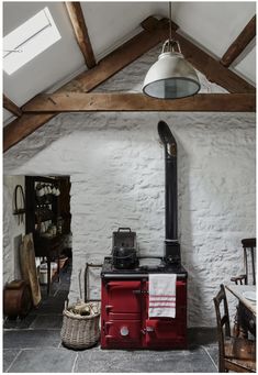 an old fashioned stove in the corner of a room with exposed beams and stone walls