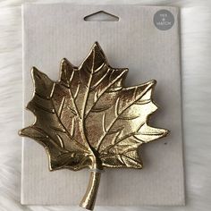 a gold leaf brooch sitting on top of a card