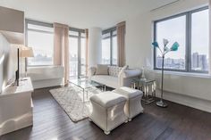 a living room filled with furniture and large windows next to a wooden floored floor