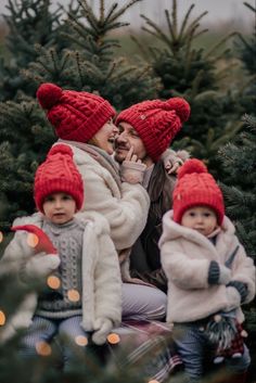 a woman and two children sitting on top of a christmas tree